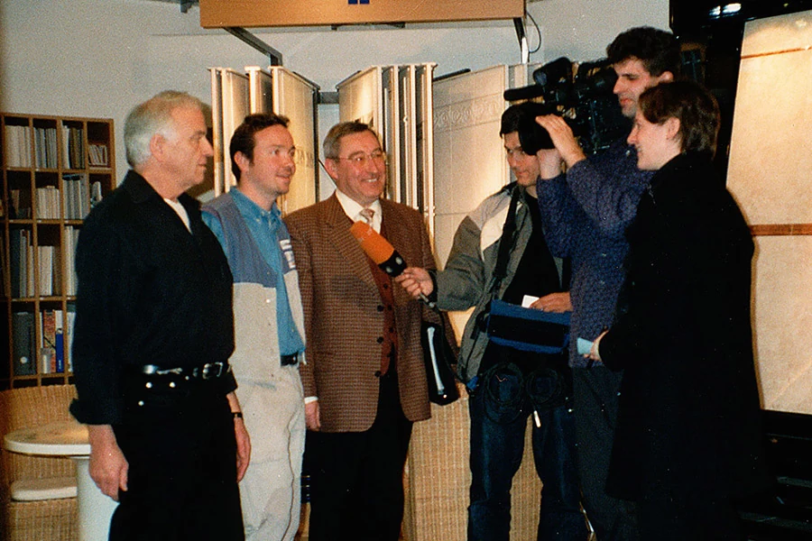 Fernsehinterview in der Fliesenausstellung, ein Kameramann filmt, im Hintergrund Musterfliesen an Schwenktafeln